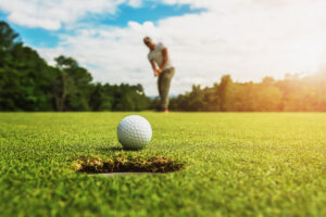 Mann beim Abschlag auf dem Golfplatz mit Bergpanorama in Oberstaufen