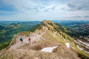 Wanderer auf einem Berggipfel mit Panorama-Blick über die Allgäuer Alpen.