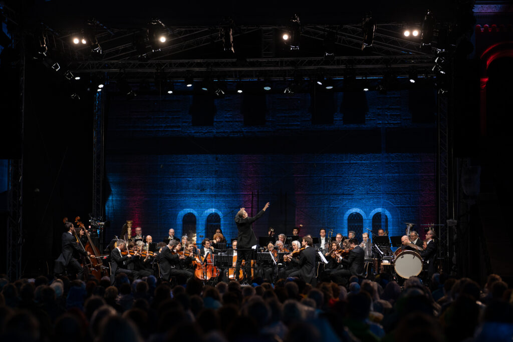 Ein klassisches Orchester und ein Dirigent bei einem Live-Auftritt während der Open-Air-Konzerte im Schlosshof.