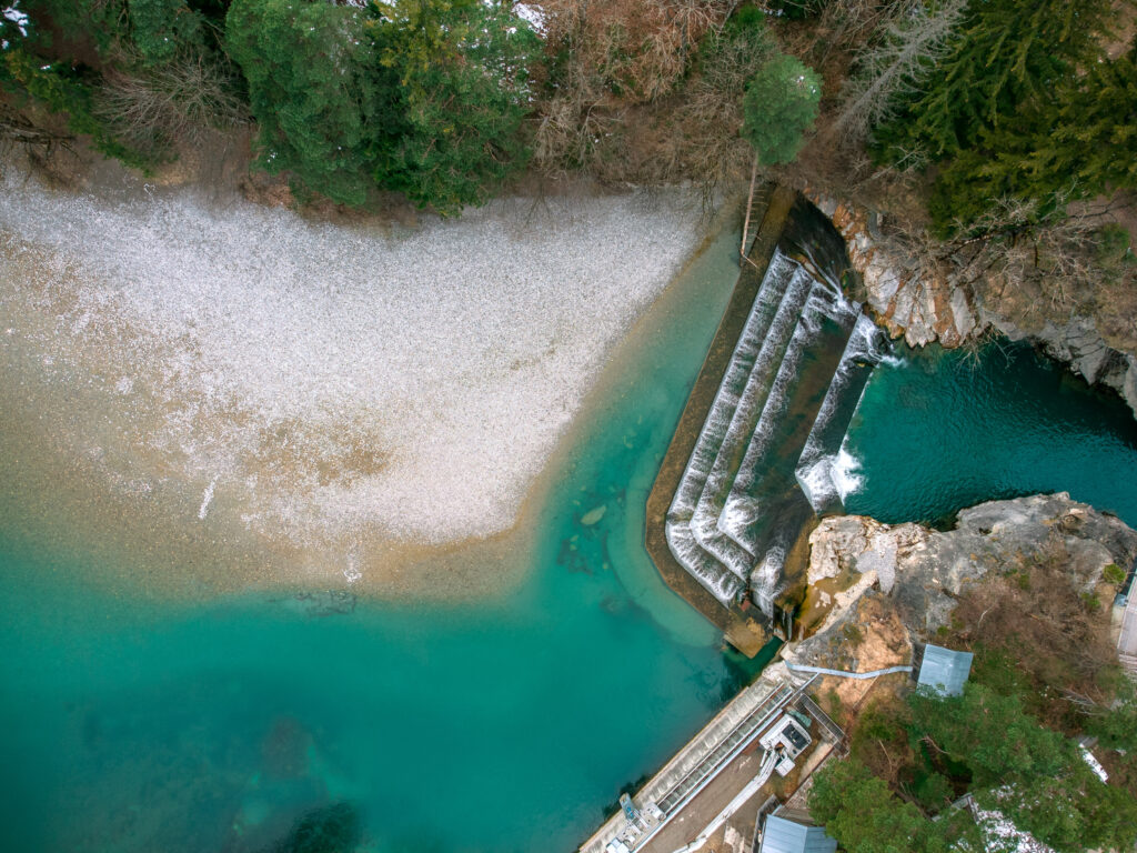 Luftaufnahme des Lechfalls bei Füssen mit leuchtend türkisblauem Wasser und Kiesbank aus der Vogelperspektive.