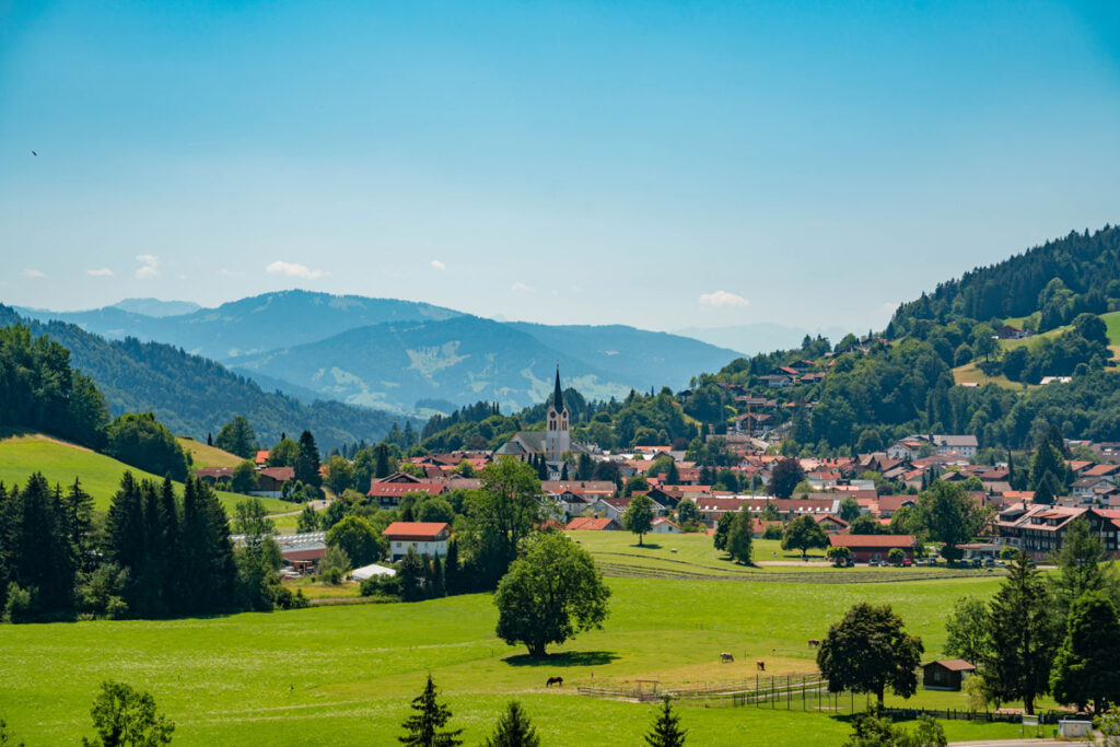 Malerische Sommeransicht von Oberstaufen mit der Pfarrkirche St. Peter und Paul vor der Kulisse der Allgäuer Alpen.