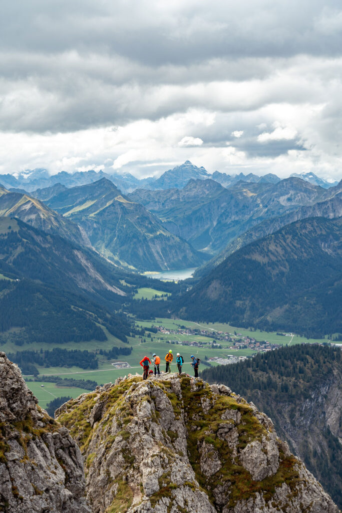 Eine Gruppe von Bergsteigern steht gesichert auf einer steilen Felsnadel am Aggenstein im Allgäu.