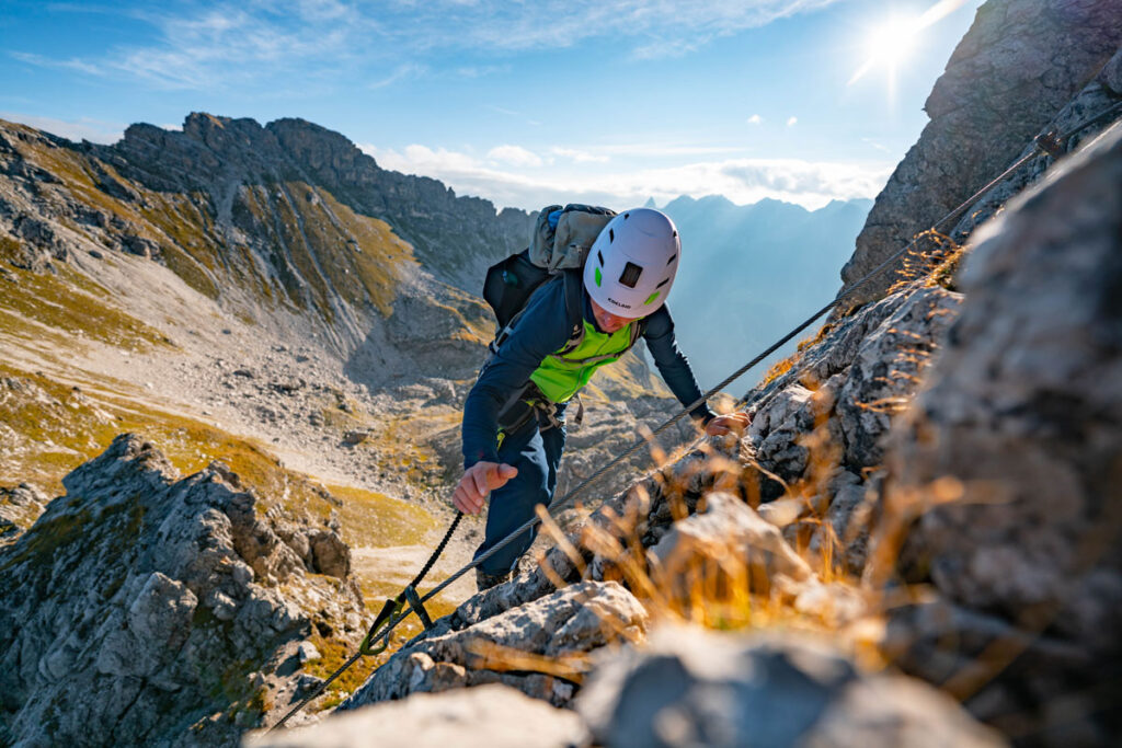 Ein Kletterer führt seine Karabiner am Stahlseil des Mindelheimer Klettersteigs im Allgäu nach.